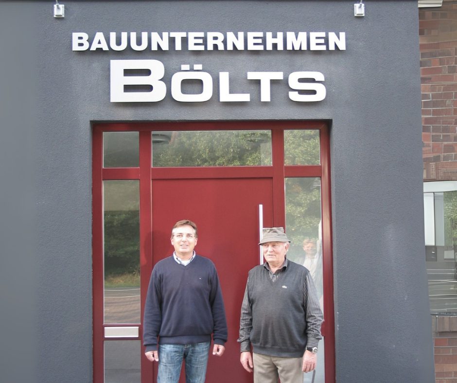Zwei Generationen des Bauunternehmens Bölts vor dem Firmeneingang – Symbol für Tradition und Beständigkeit.